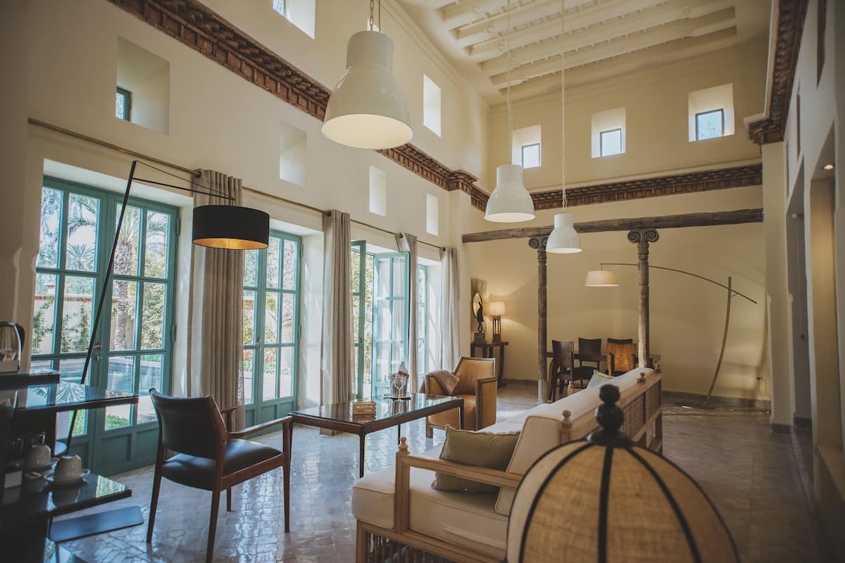 A spacious living room with a high ceiling, large windows, and a mix of modern and traditional furnishings.