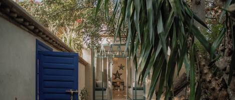 A pathway leading to a door with a star decoration, surrounded by greenery and a gravel path.