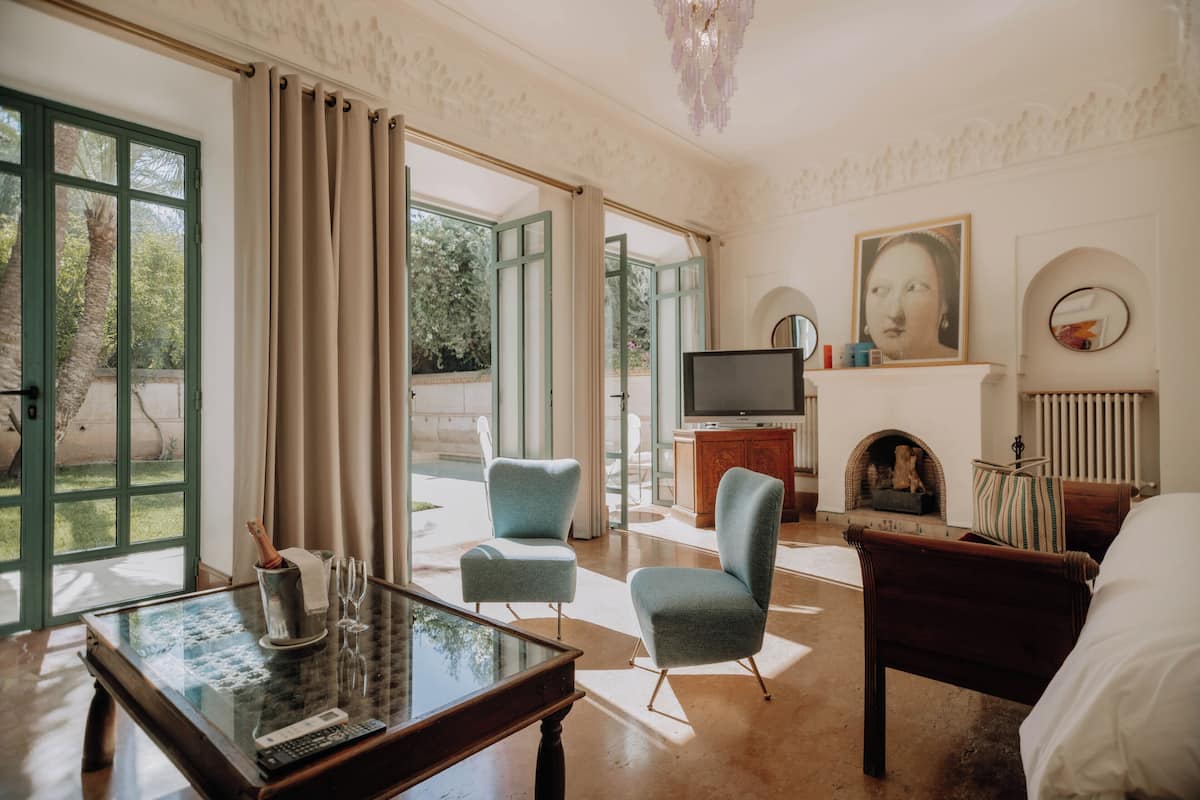 A spacious living room with a large window, a fireplace, a television, and a comfortable seating area.