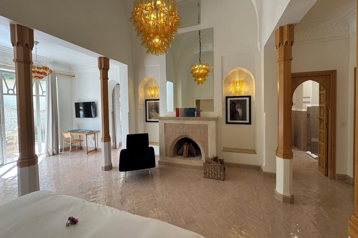 A spacious room with a fireplace, a chandelier, and a bed.