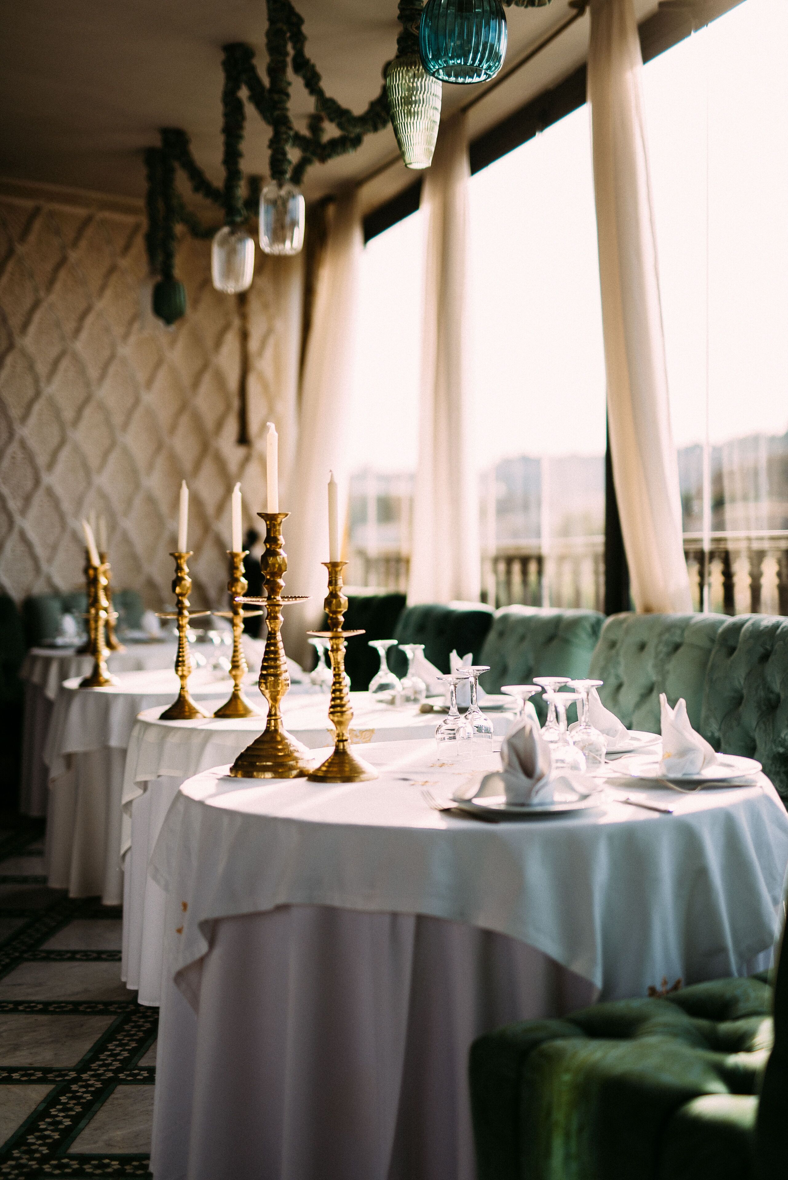 Un espace repas avec des tables rondes dressées pour le service, agrémenté de chandeliers dorés et de nappes blanches.