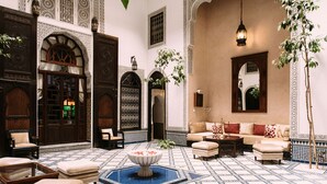 A traditional Moroccan interior with ornate arches, a patterned floor, and a cozy seating area. - Riad Maison Bleue And Spa (Fes)