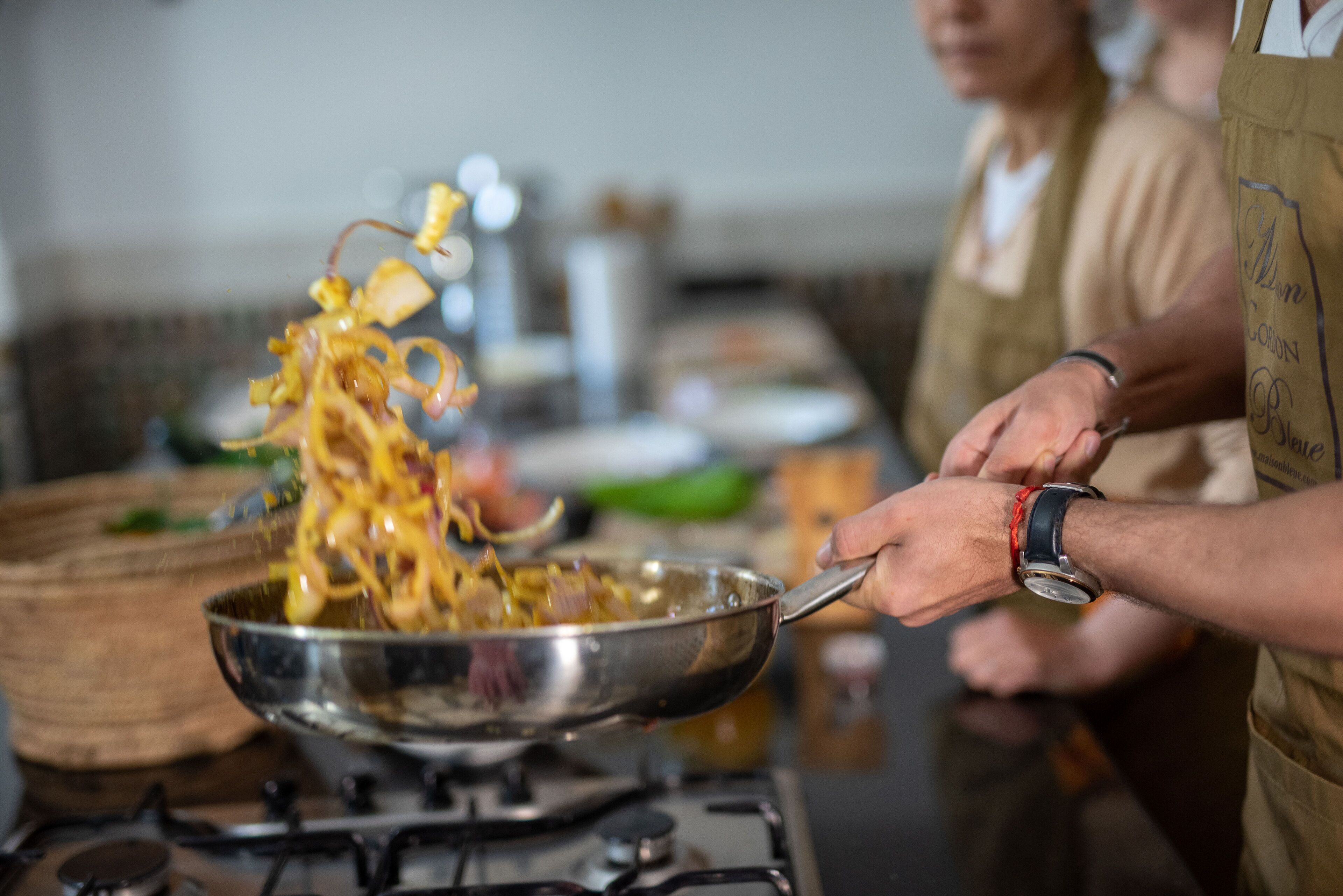 Una persona cocinando con una sartén sobre un fogón.