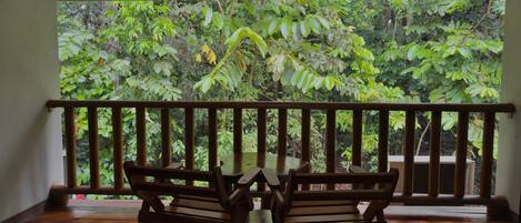 Una terraza de madera con mesa y sillas, con vistas a un jardín exuberante.
