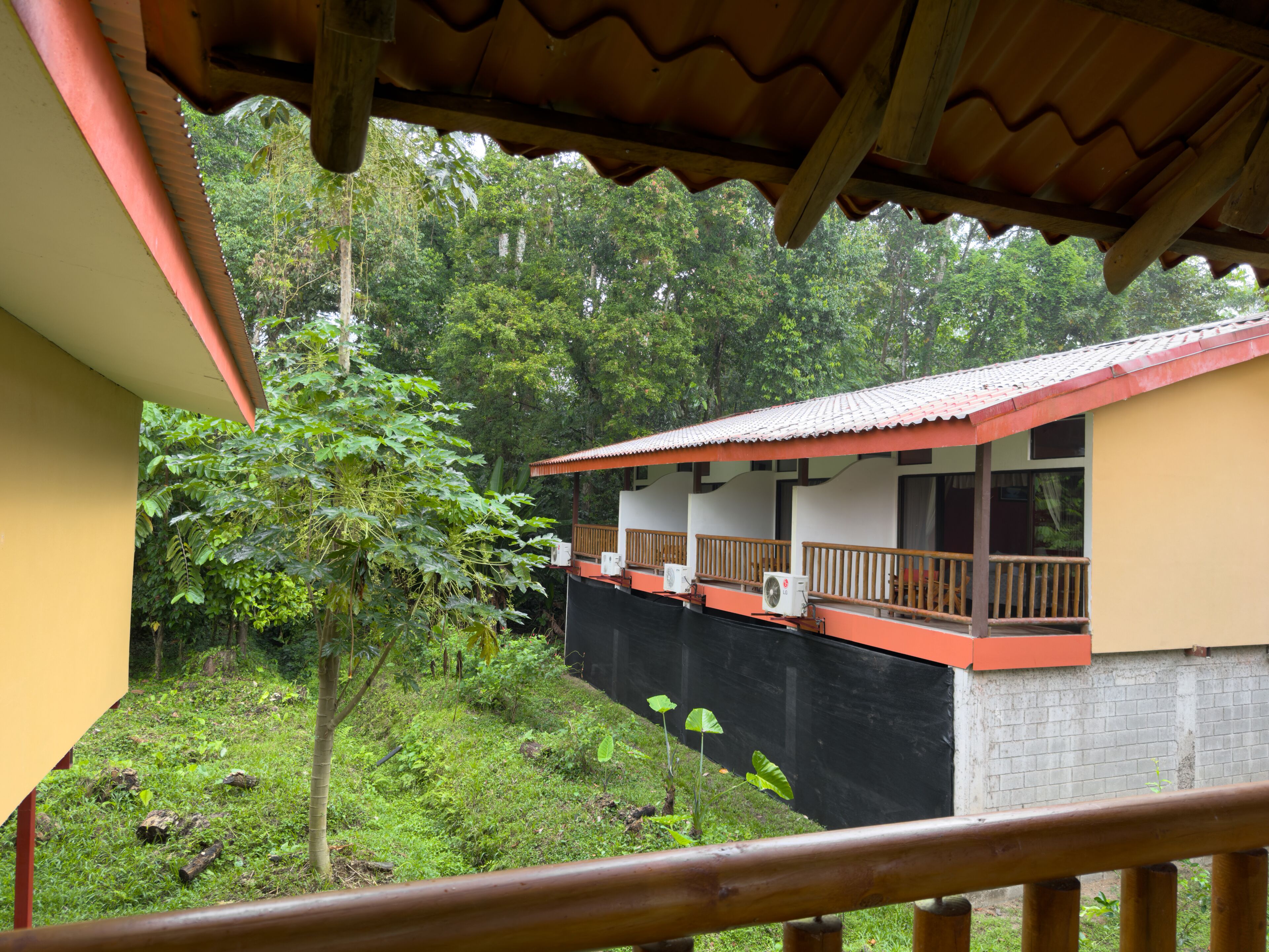 A two-story building with a balcony, surrounded by lush greenery.