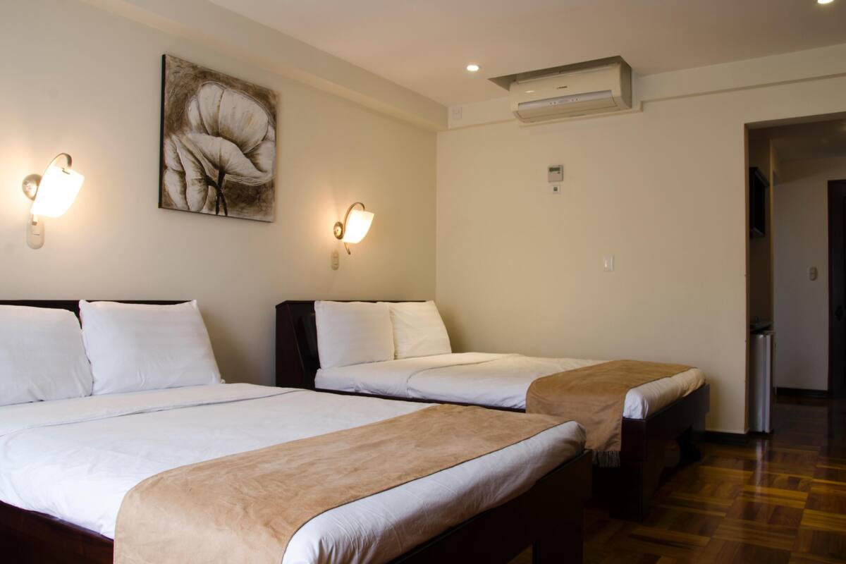 Ein Hotelzimmer mit zwei Betten, einer Wandklimaanlage und zwei Wandleuchten.