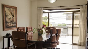 Een vergaderzaal met een grote tafel, meerdere stoelen, een telefoon en een vaas met bloemen.