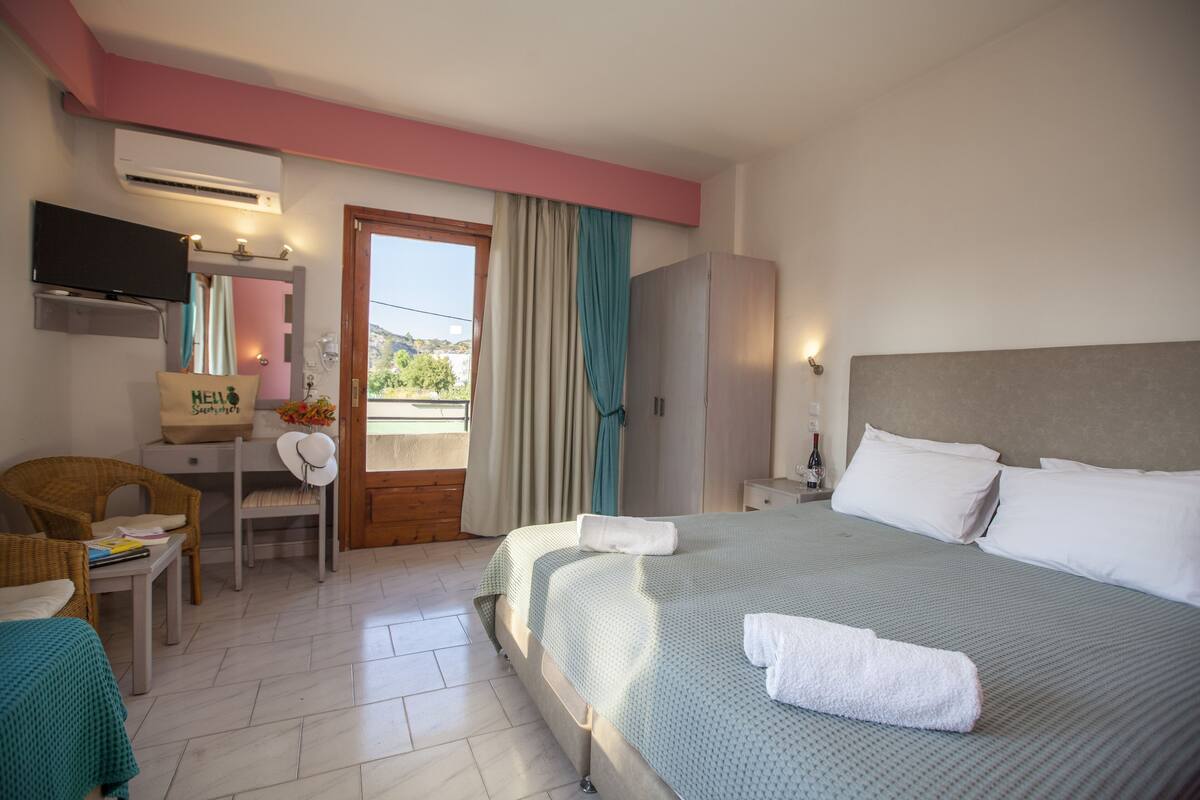 A hotel room with a bed, a desk, a chair, a television, and a window with curtains.
