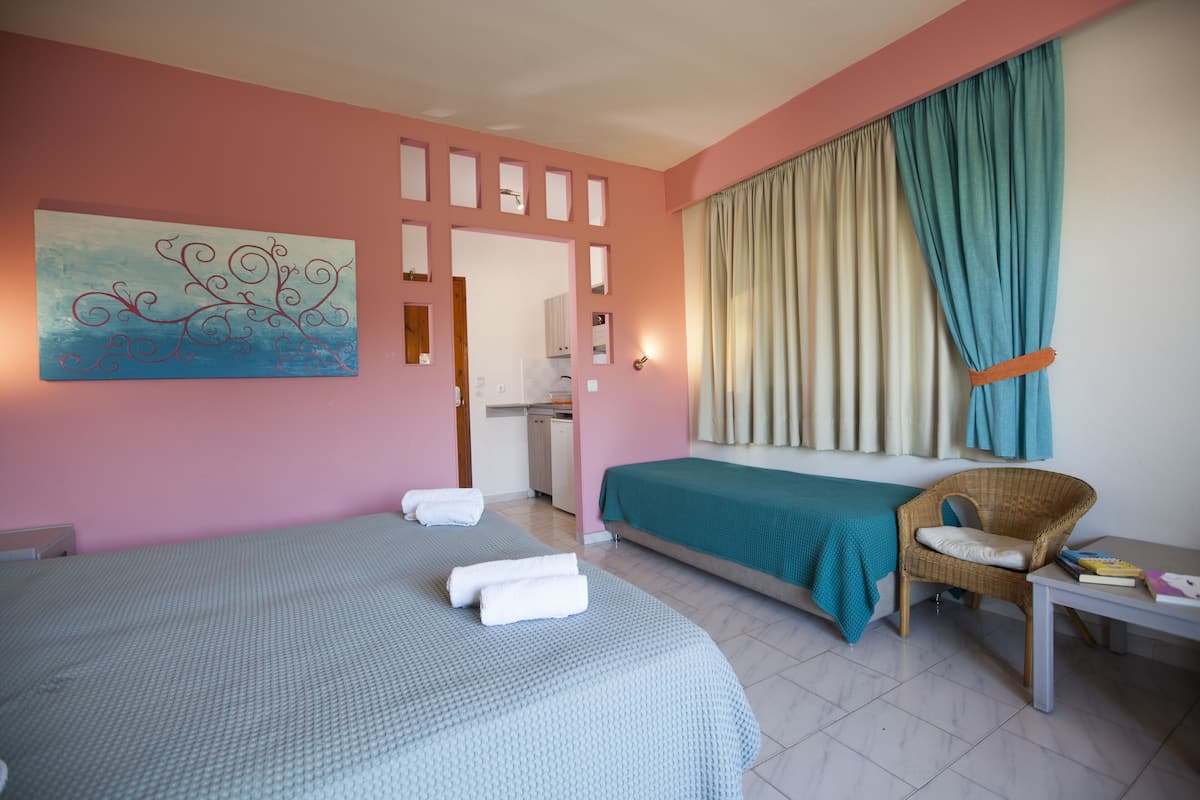 A bedroom with a bed, a chair, a table, and a painting on the wall.