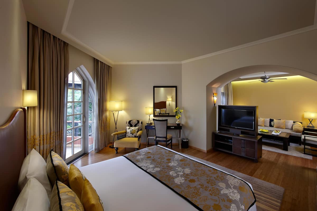 A hotel room with a large bed, a desk, a television, and a sofa.