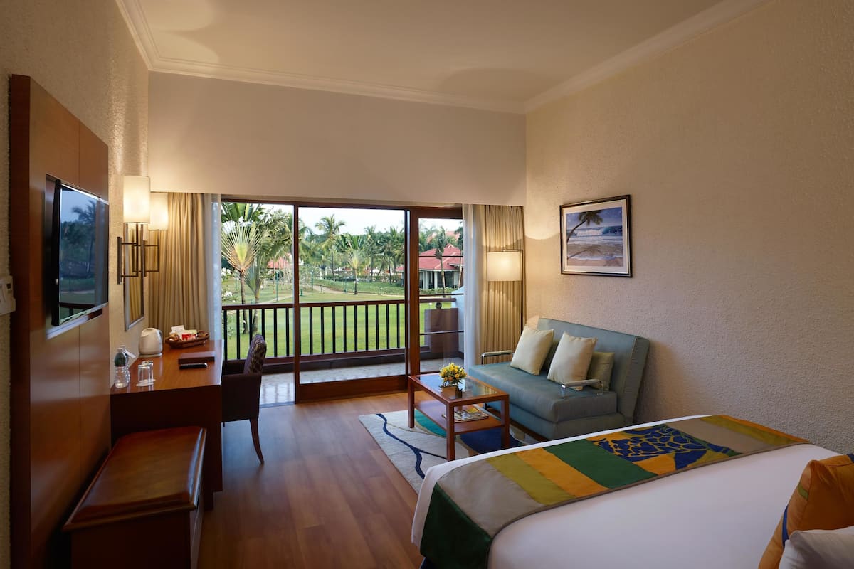 A hotel room with a balcony, a sofa, a bed, a desk, and a TV.