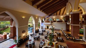 A spacious indoor area with multiple dining tables and chairs, high ceilings with wooden beams, and large arched windows. - Caravela Beach Resort (Varca)