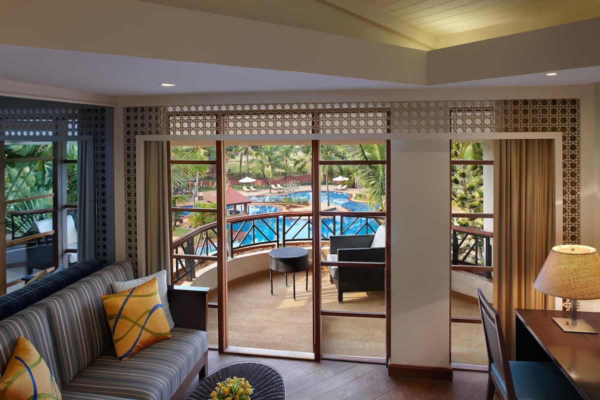 A room with a sofa, a table, and a view of an outdoor pool area.