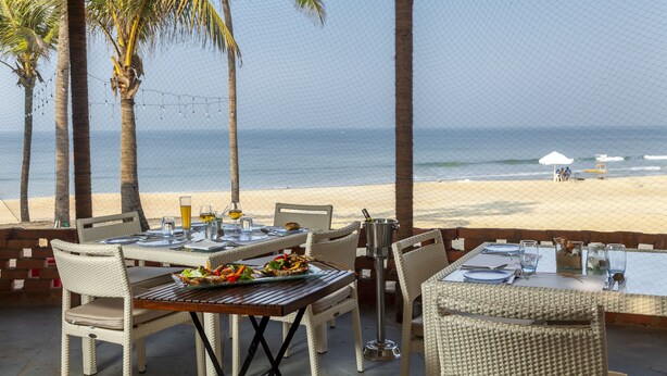 A beachside dining area with tables set for two, overlooking the ocean. - Caravela Beach Resort (Varca)