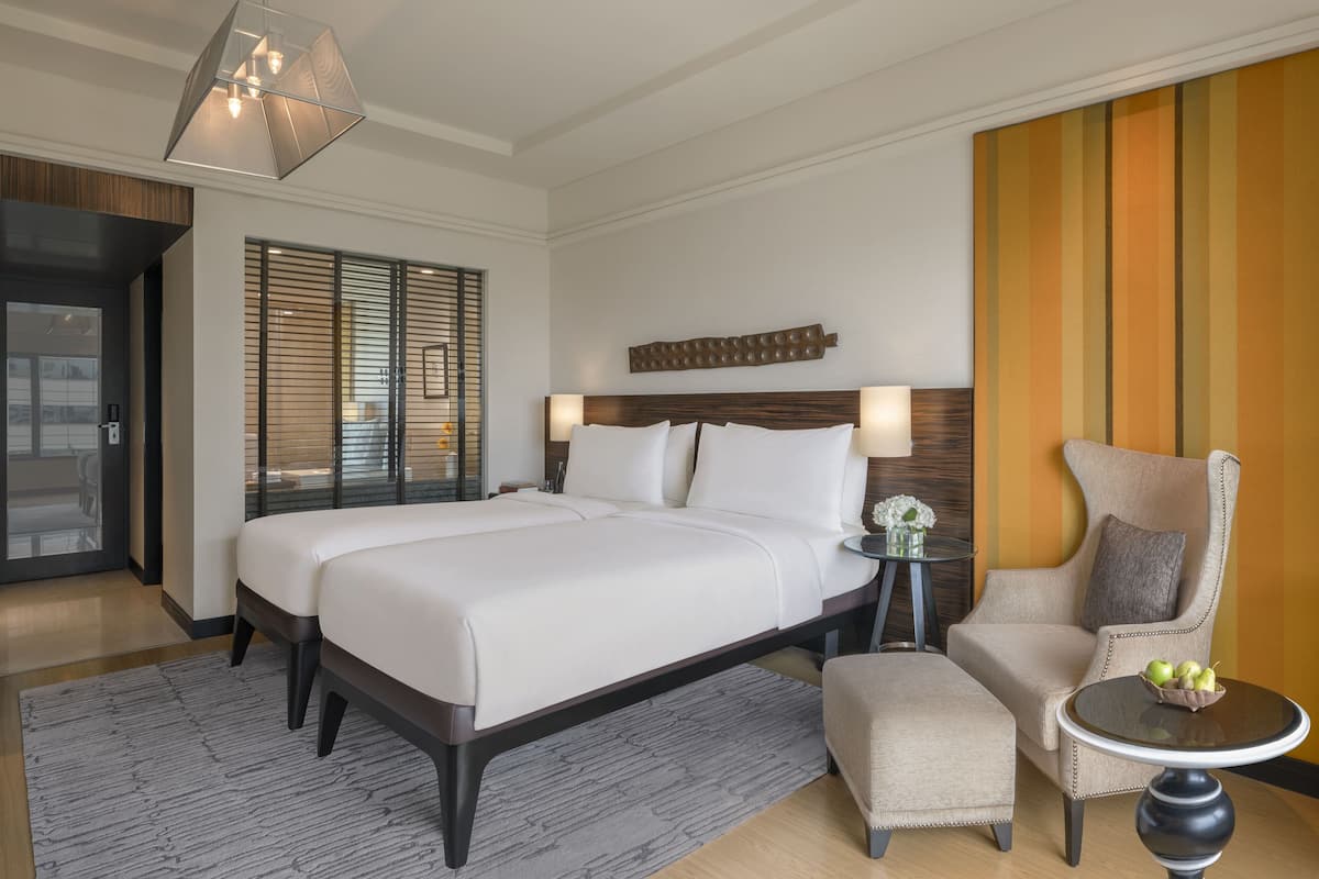 Ein Hotelzimmer mit einem großen Bett, einem Sessel, einem kleinen Tisch und einer dekorativen Wandverkleidung.