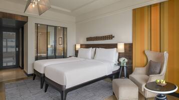 Una habitación de hotel con una cama grande, una silla, una mesita pequeña y un panel decorativo en la pared.