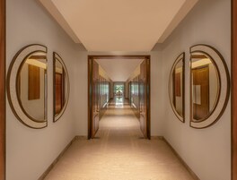 Un pasillo con paredes espejadas y una puerta de madera al final.