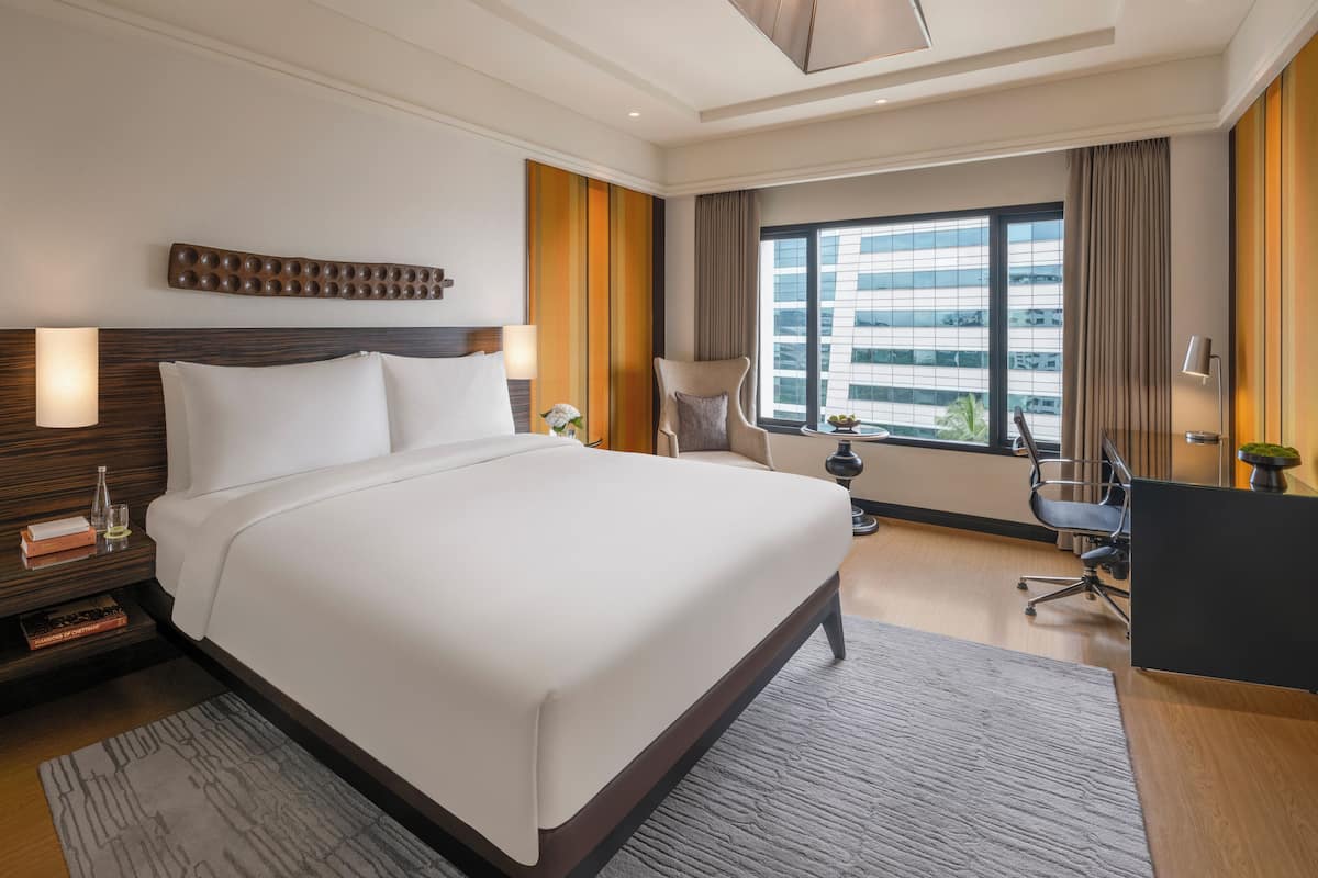 Ein modernes Hotelzimmer mit einem großen Bett, einem Schreibtisch und Blick auf die Stadt.