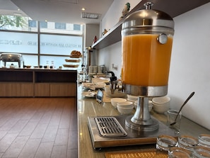 A juice dispenser in a hotel kitchen with a window view. - Hotel San Agustin Riviera (Lima)