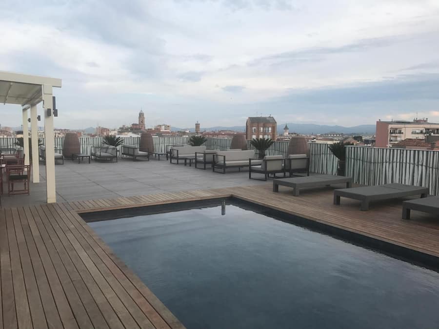 Terraza en la azotea con piscina, zona de estar y vistas a la ciudad.