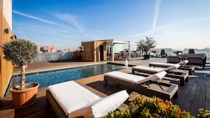 A rooftop pool area with lounge chairs, a small pool, and a wooden deck. - Hotel Urpi (Sabadell)