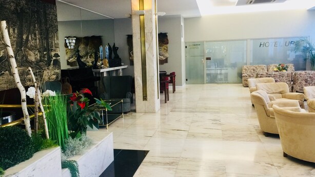 A hotel lobby with a reception desk, seating area, and a glass door labeled "HOTEL UP". - Hotel Urpi (Sabadell)