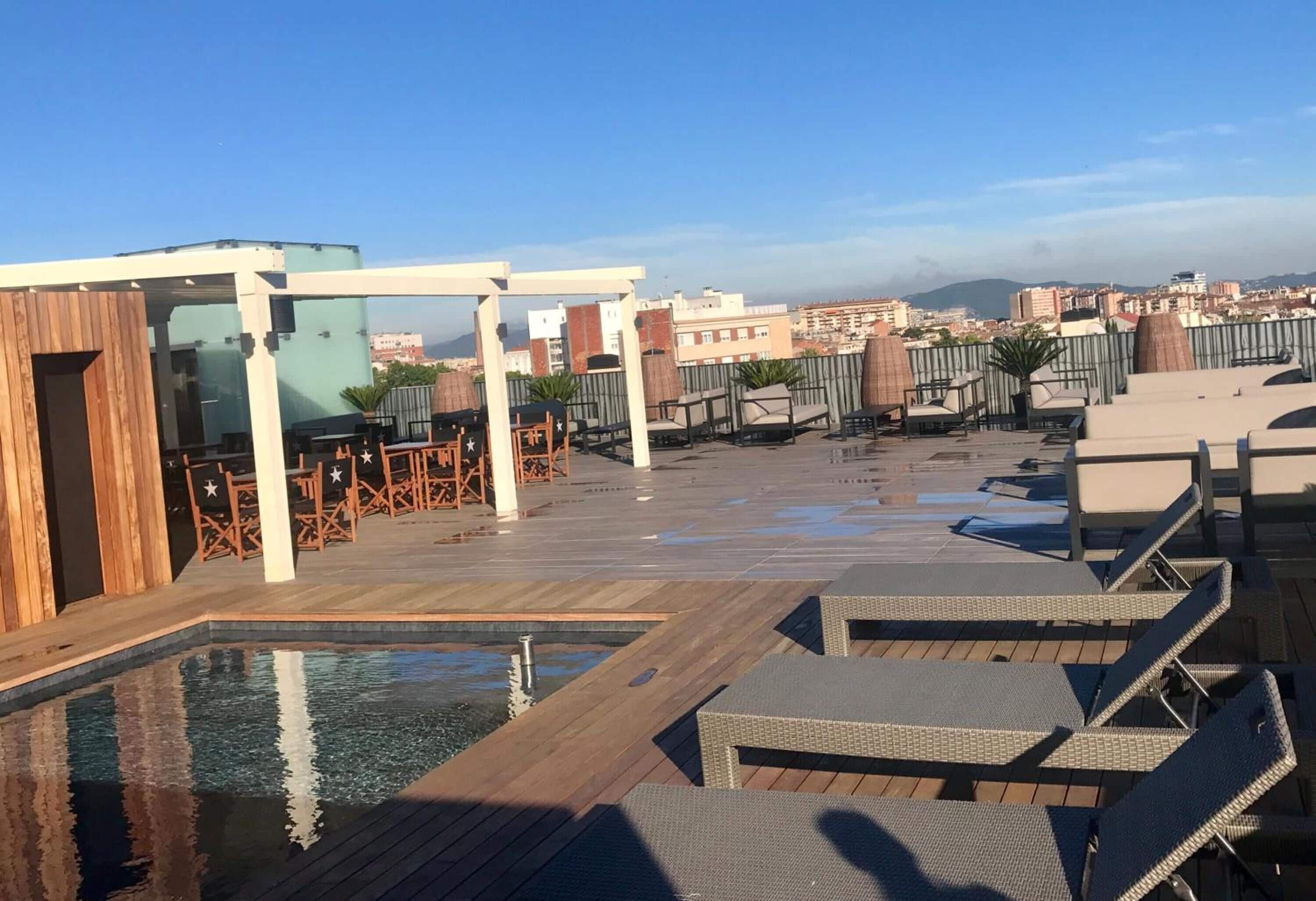 Una terraza en la azotea con sillones de descanso, piscina y vistas a la ciudad.