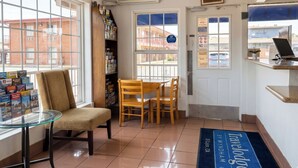 Un espace d’accueil comprenant une table en verre, une chaise en bois, une bibliothèque et une porte avec une pancarte.