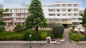 A multi-story hotel with balconies, a landscaped garden, and outdoor seating areas.