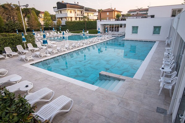 A swimming pool area with multiple pools, sun loungers, and umbrellas. - Hotel Vena D'Oro (Abano Terme)