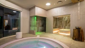 Área de spa com hidromassagem, sauna de vidro e chuveiro separado.