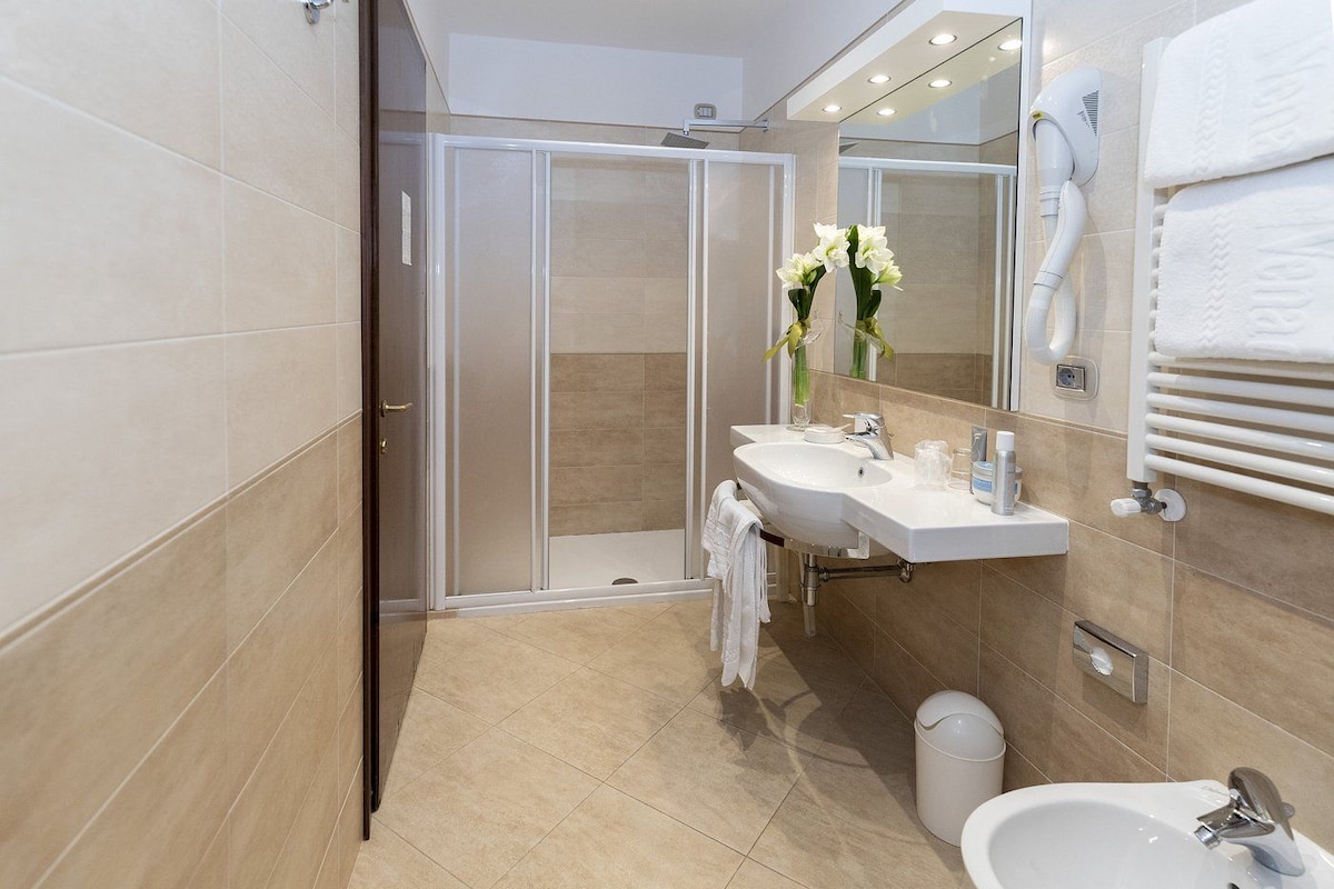 A modern bathroom with a walk-in shower, a vanity with a mirror, and a bidet.