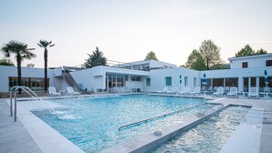 A modern pool area with a rectangular pool, white lounge chairs, and a staircase leading to an upper level.