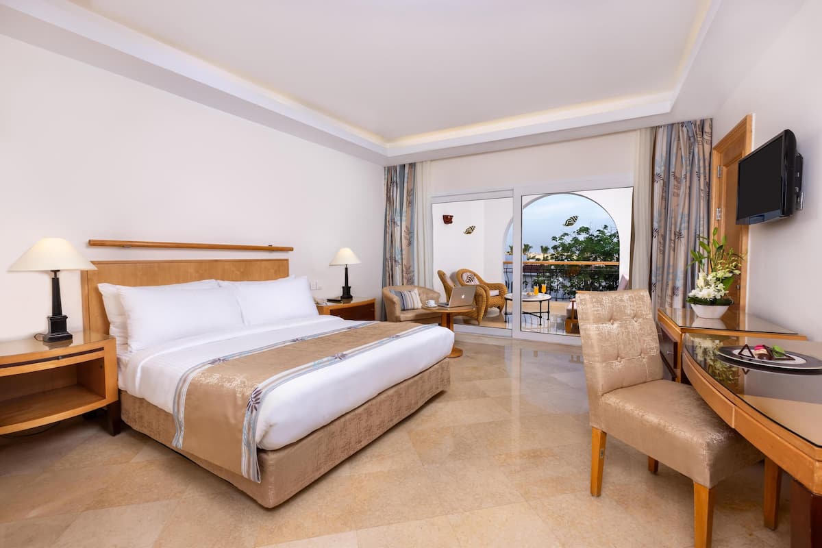 A hotel room with a large bed, a desk, a chair, and a TV.