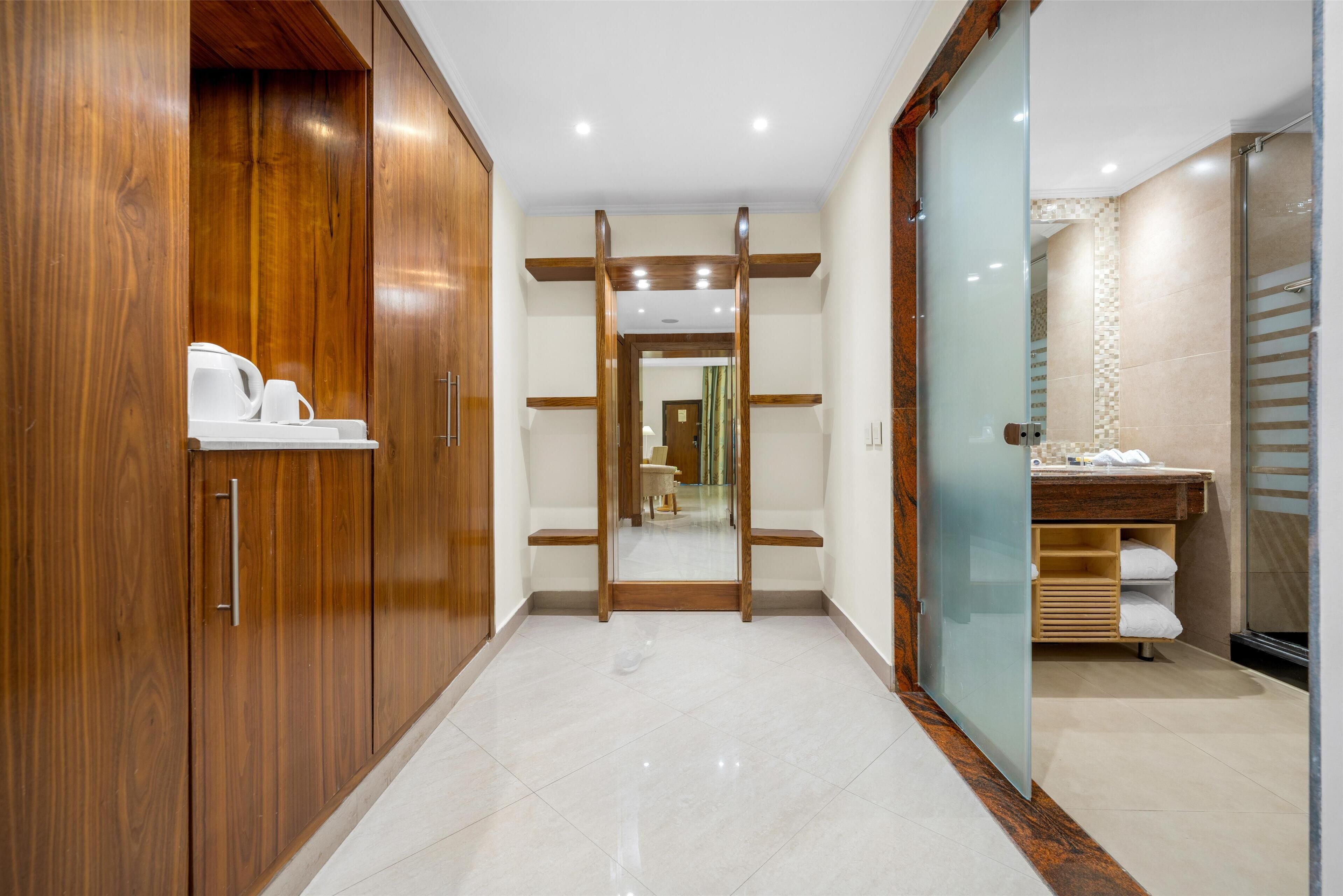 Een moderne badkamer met een douchecabine van glas, een houten wastafelmeubel en een betegelde vloer.