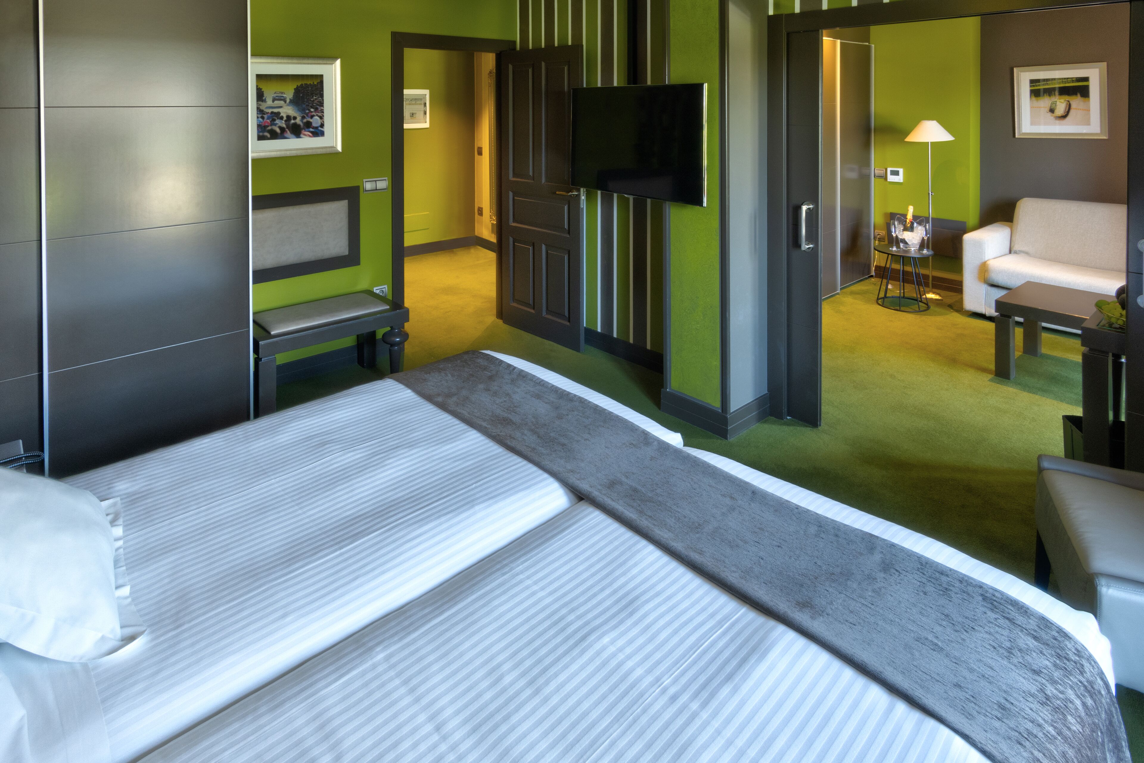 Une chambre d’hôtel avec un lit, une télévision, un canapé et une petite table.