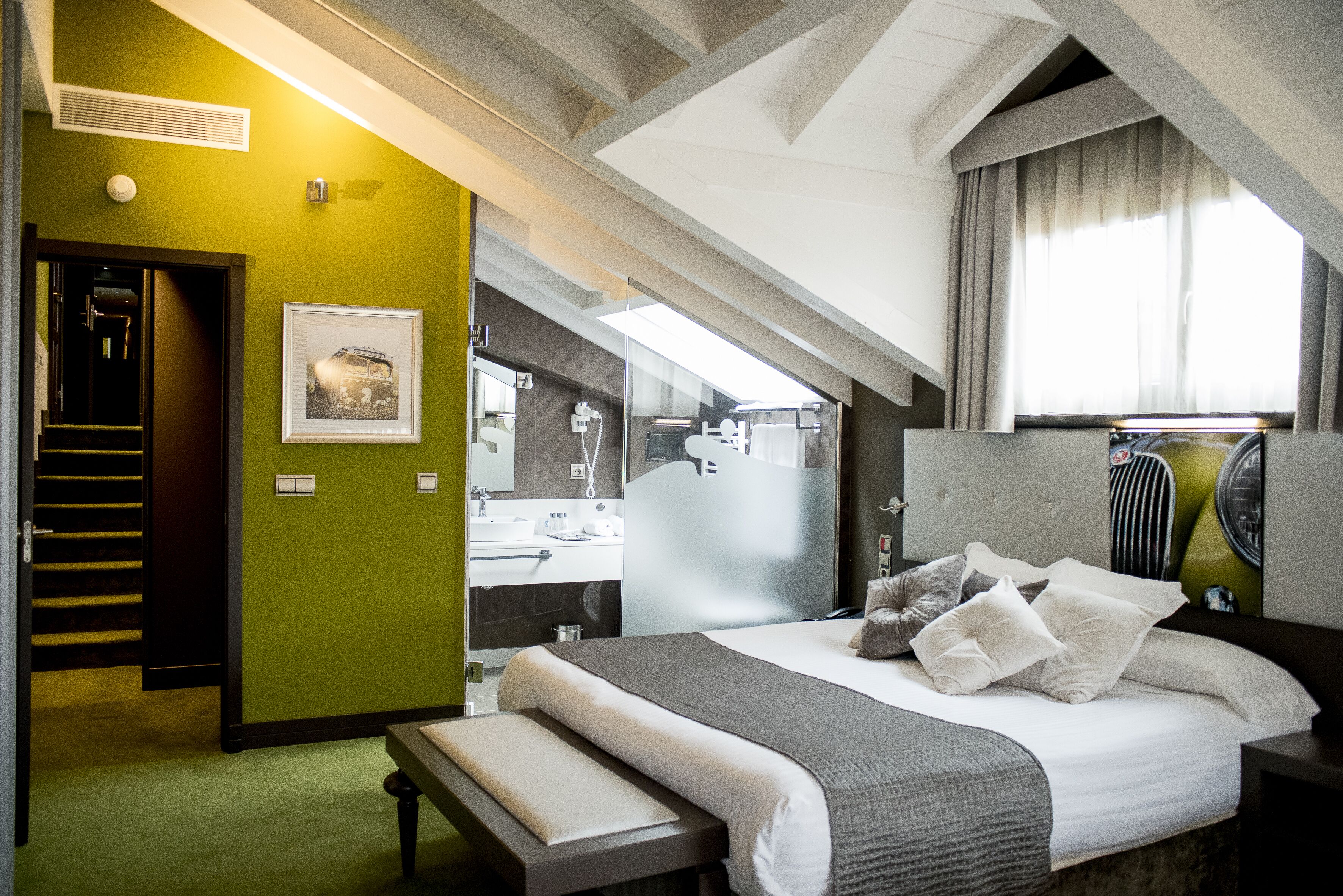 Een moderne hotelkamer met een groot bed, een badkamer met spiegel en een trap naar een hoger niveau.