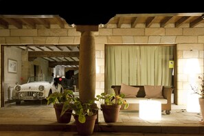 A stone building with a car parked in front, a sofa, and potted plants. - Costa Esmeralda Suites (Suances)