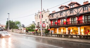 A building with a stone facade, multiple balconies, and red awnings. - Costa Esmeralda Suites (Suances)