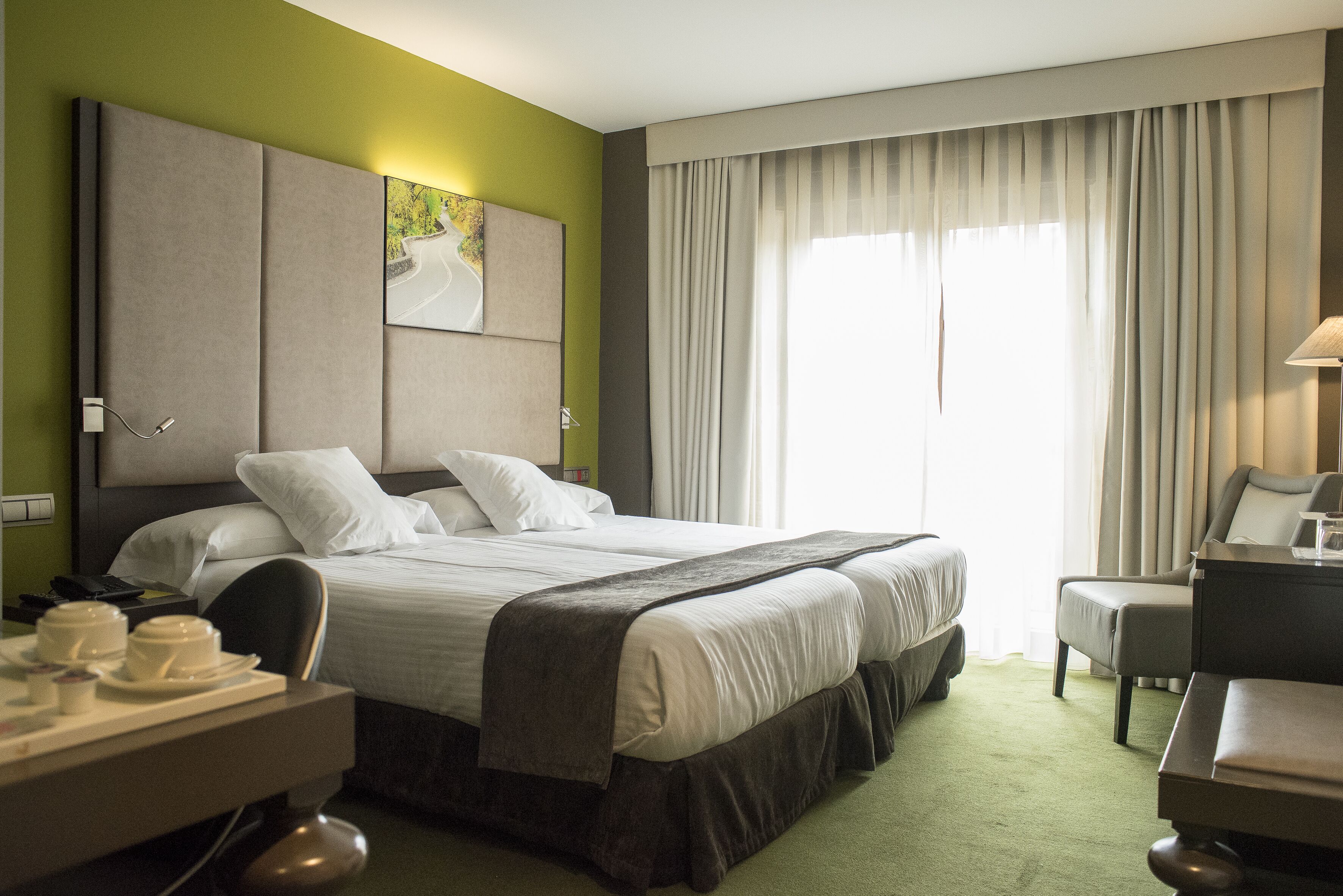 Une chambre d’hôtel avec un grand lit, un bureau avec une lampe et une vue sur l’extérieur par la fenêtre.