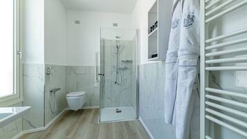 A modern bathroom with a glass-enclosed shower, a toilet, a vanity with a mirror, and a towel rack.