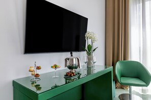 Een moderne woonkamer met een flatscreen televisie aan de wand, een groene consoles met decoratieve objecten, en een groene fauteuil.