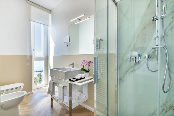 A modern bathroom with a glass shower, a sink, and a toilet.
