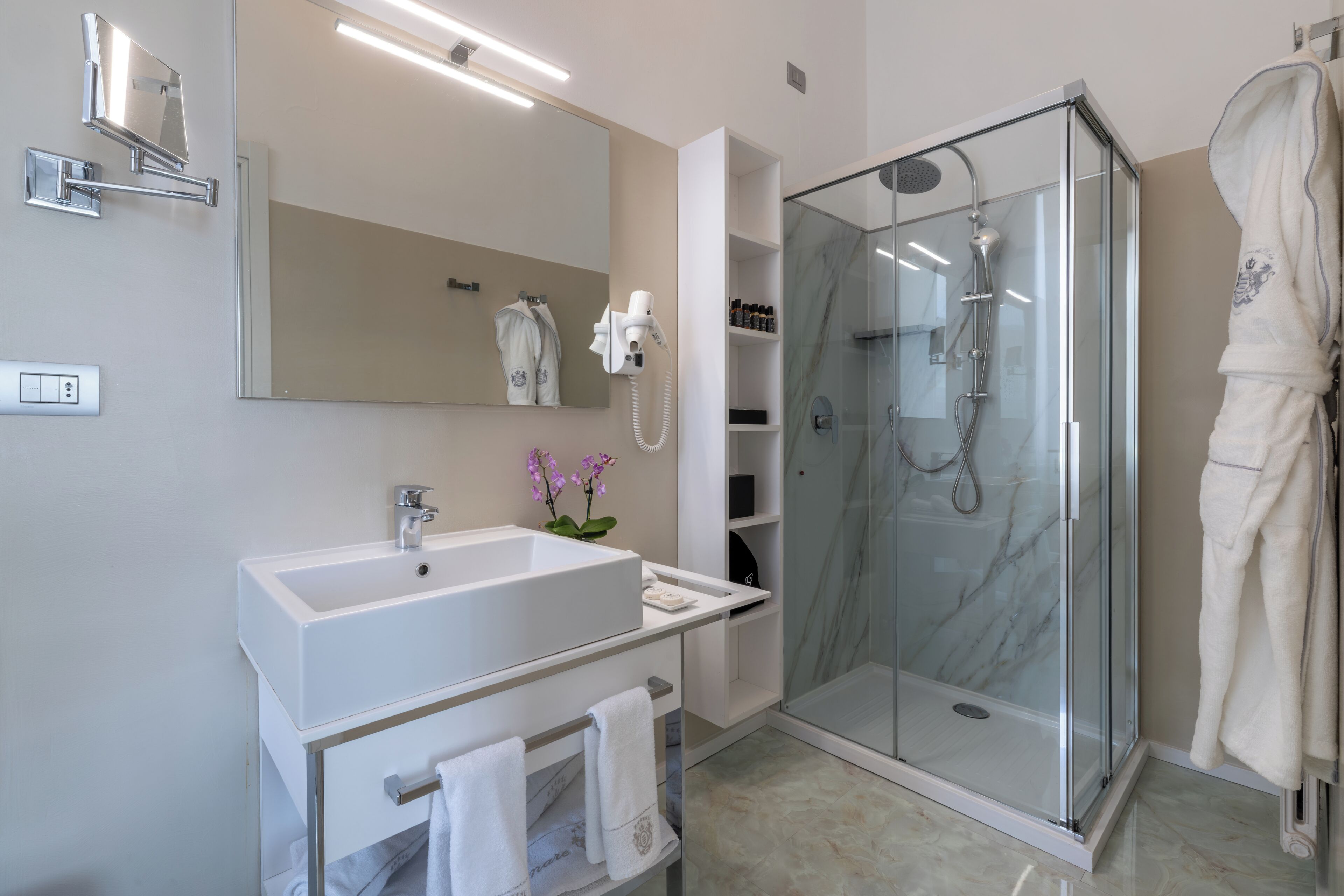 Une salle de bain moderne avec un lavabo blanc, un miroir et une douche en verre.