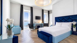 Une chambre d’hôtel moderne avec un grand lit, un bureau, une chaise et une vue sur l’océan.