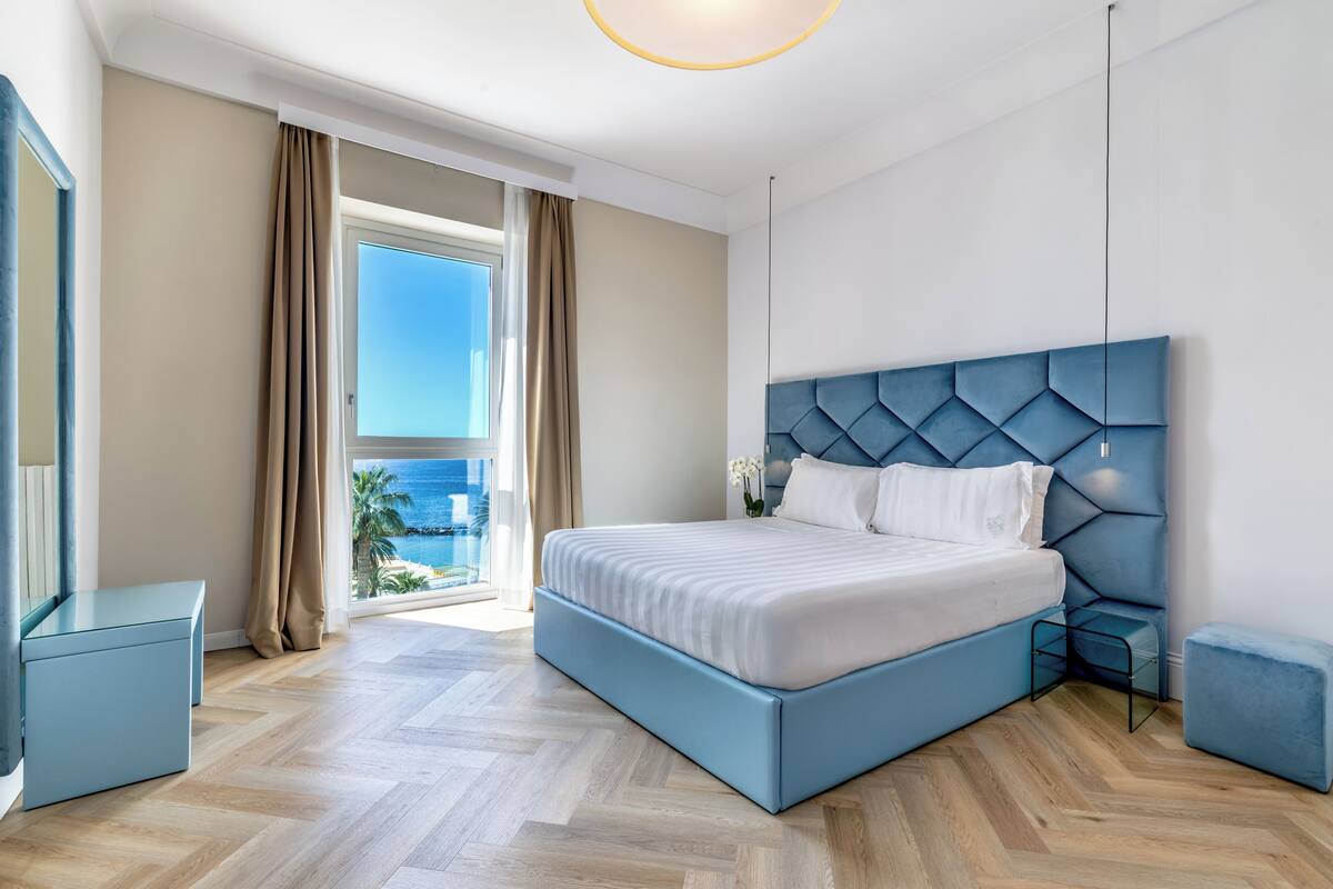 Une chambre moderne avec un grand lit, une vue sur l’extérieur et un balcon.