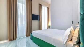 Una habitación de hotel con cama, cortinas, un televisor de pantalla plana y una mesita de noche.