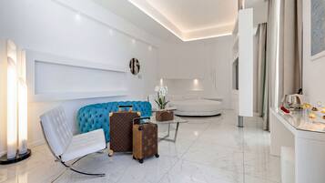 A modern living room with a white sofa, a blue accent chair, and a Louis Vuitton suitcase.