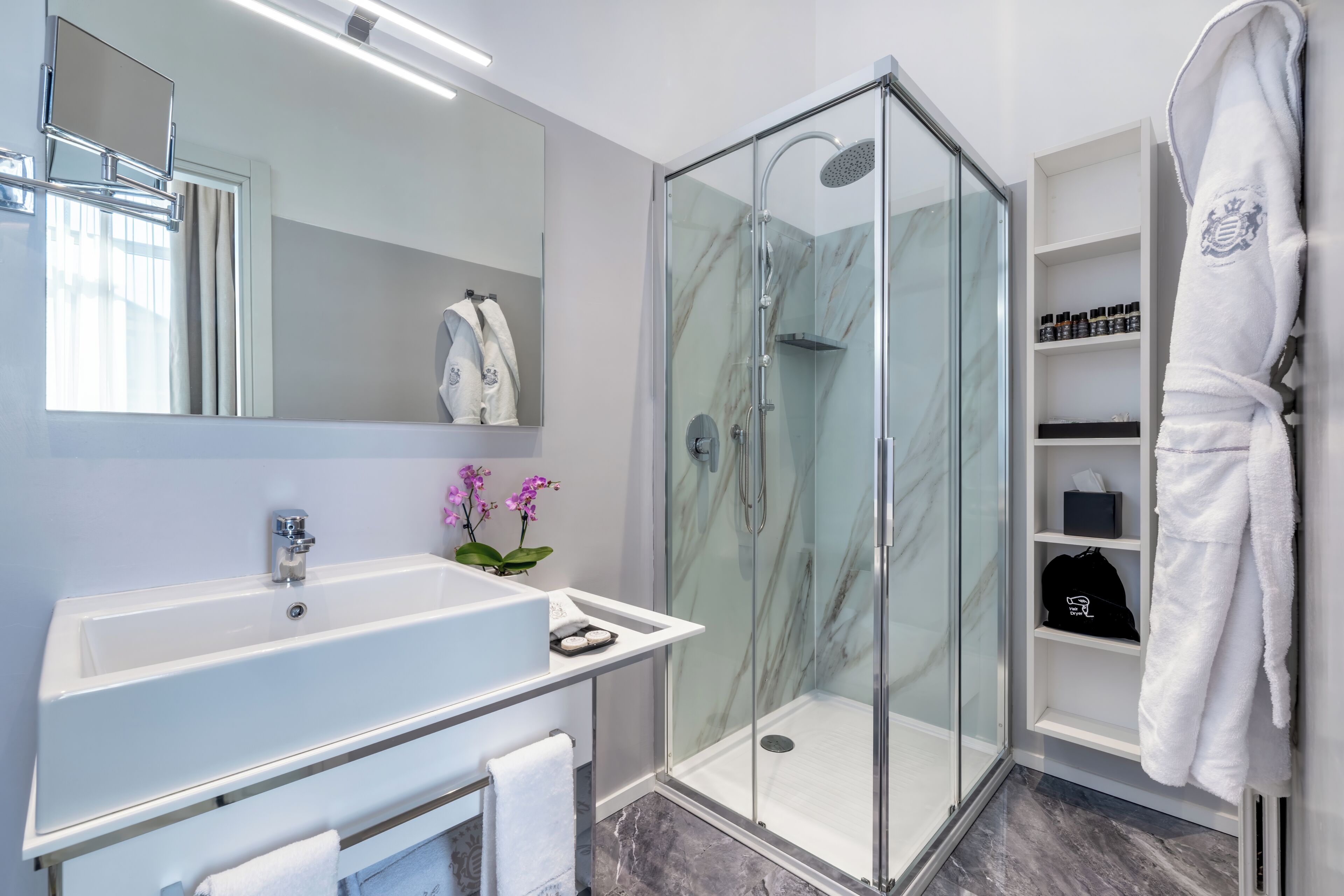 Une salle de bain moderne avec une douche à parois de verre, un lavabo blanc et un miroir.