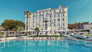 Un grand bâtiment blanc doté de balcons et d’un espace piscine à l’avant.